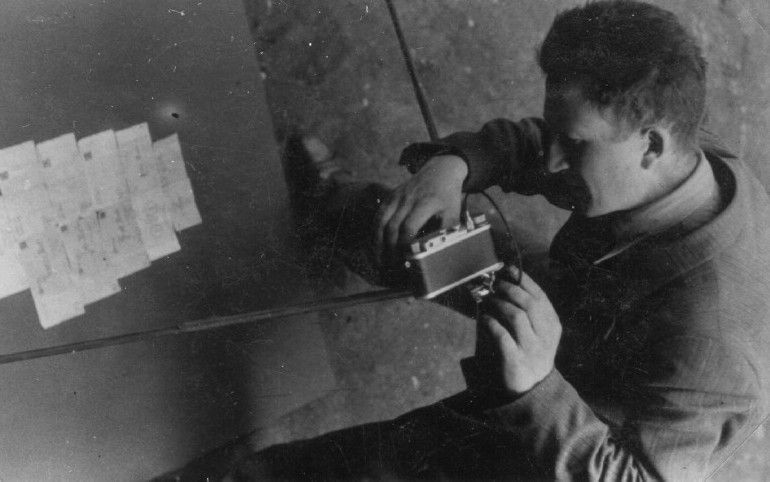 Mendel Grosman photographing ghetto currency bills for an album of the Lodz ghetto.